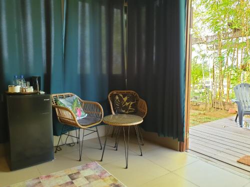 two chairs and a table in a room with curtains at Houttuyn Wellness River Resort in Paramaribo