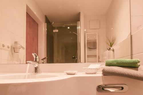 Baño blanco con lavabo y espejo en Eurostar Hotel, en Castrop-Rauxel