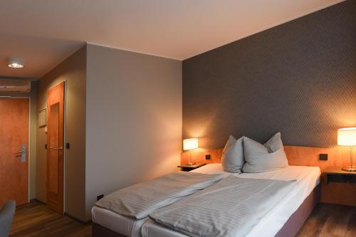 a bedroom with a large bed with two lamps at Eurostar Hotel in Castrop-Rauxel