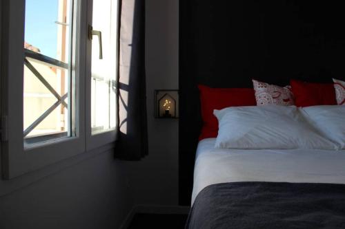 a bed with red and white pillows next to a window at DISNEYLAND PARIS NEW STUDIO SUITE DESIGN in Bailly-Romainvilliers