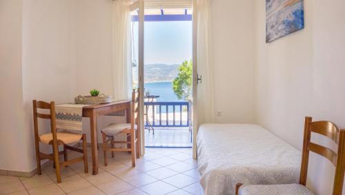 a room with a table and a bed and a balcony at Sunrise Limnionas Apartments in Marathokampos