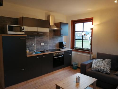 a kitchen with black cabinets and a living room at Parkweg Lodge in Faak am See