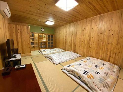 two beds in a room with wooden walls at SYUkuhaku matuenosato / Vacation STAY 65782 in Matsue