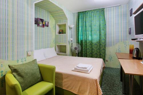 モスクワにあるフレガッ アット パヴェレツカヤのベッド1台と緑の椅子が備わる小さな客室です。