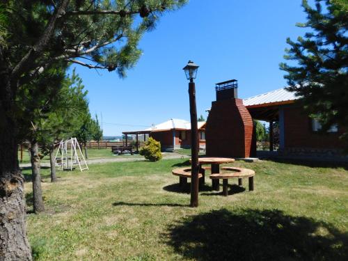 un parque con 2 mesas de picnic y un parque infantil en Cabañas Atrapasueños en Trevelín