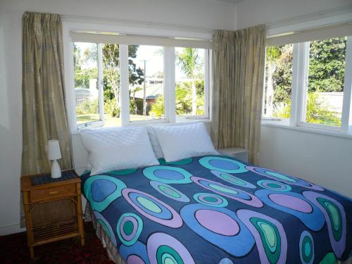 a bedroom with a bed and two windows at Ridge Cottage - Oneroa Holiday Home in Oneroa