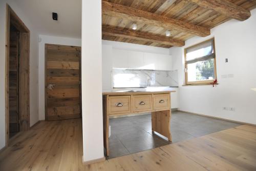 uma cozinha com uma secretária de madeira num quarto com uma janela em Chalet n. 5 em Carano