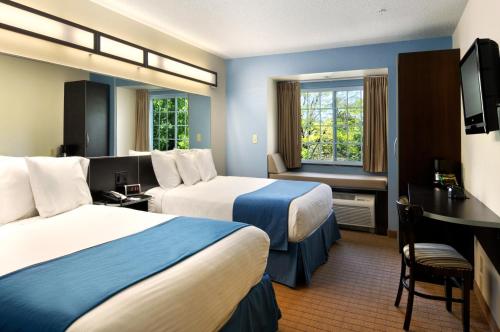um quarto de hotel com duas camas e uma secretária em Microtel Inn & Suites Bath em Bath