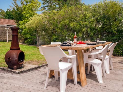 a wooden table with white chairs and a grill at On The Green - Pauanui Holiday Home in Pauanui