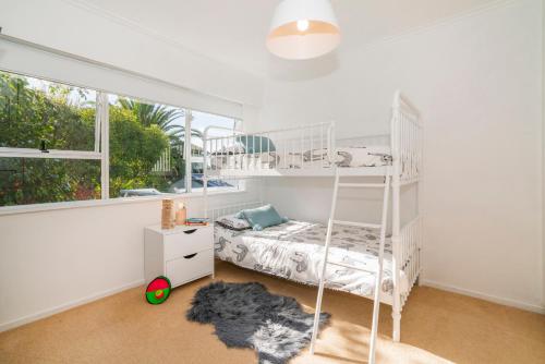 a white bedroom with a bunk bed and a window at Patton's Place - Pauanui Holiday Home in Pauanui