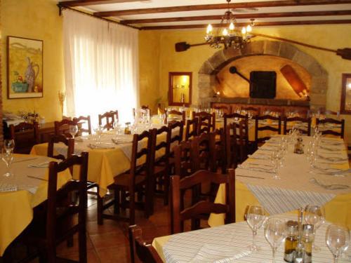 a dining room with tables and chairs with white tablecloths at Hotel Restaurante el Horno in La Puebla de Valverde