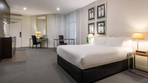 a hotel room with a bed and a desk at Oaks Melbourne on Collins Hotel in Melbourne