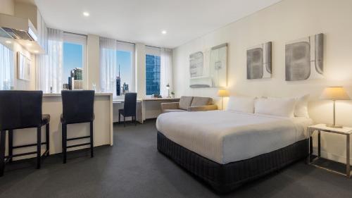 ein Hotelzimmer mit einem Bett und einem Schreibtisch in der Unterkunft Oaks Melbourne on Collins Suites in Melbourne
