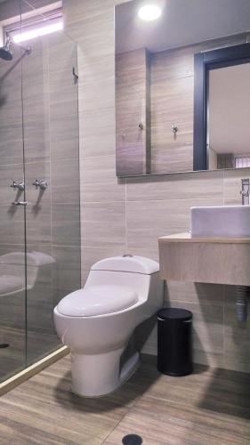 a bathroom with a toilet and a sink and a mirror at Hotel WLH Silver Corferias in Bogotá