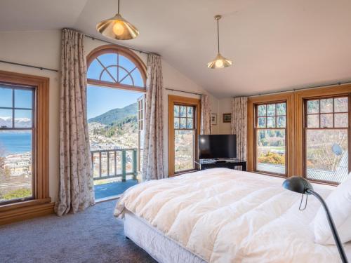 a bedroom with a large bed and large windows at McAlister House - Queenstown Holiday Home in Queenstown