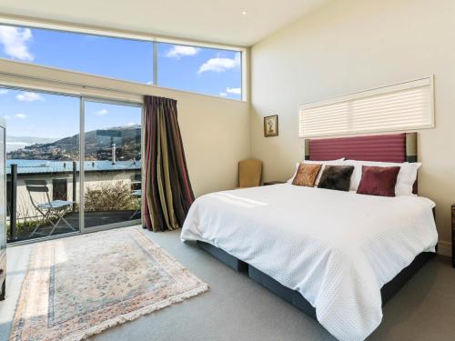 um quarto com uma cama grande e uma janela grande em Lake Views on Yewlett - Queenstown Holiday Home em Queenstown
