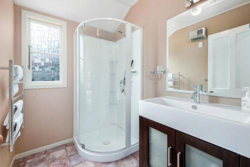 a bathroom with a shower and a white sink at Central Peach - Queenstown Holiday Home in Queenstown