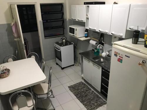 a small kitchen with a table and a refrigerator at Quarto aconchegante nas Mercês in Curitiba