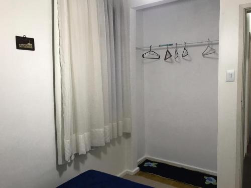 1 dormitorio con cortinas blancas y ventana en Quarto aconchegante nas Mercês en Curitiba