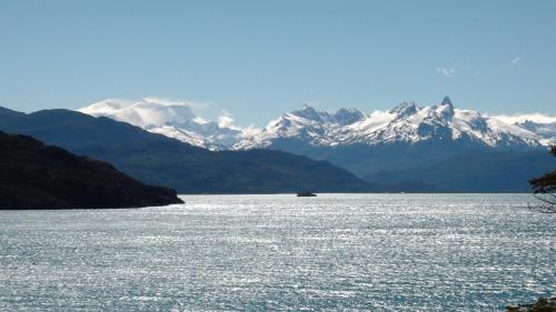 a view of a large body of water with snow capped mountains at Lodge El Mirador De Guadal in Puerto Guadal