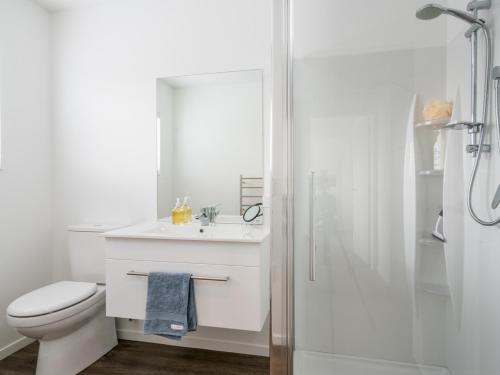 a white bathroom with a toilet and a shower at Ruakaka Sands - Ruakaka Holiday Home in Ruakaka