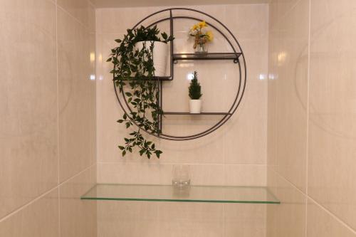 a glass shelf with flowers and a mirror on a wall at The Lavenders in Bracknell