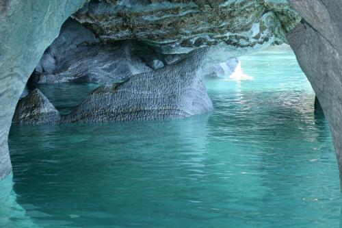a cave with blue water and rocks in it at Lodge El Mirador De Guadal in Puerto Guadal