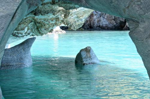 a rock in the water in front of a cave at Lodge El Mirador De Guadal in Puerto Guadal