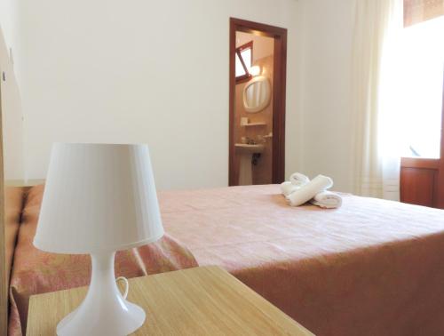 a bed with a white lamp on a table at Hotel Saturno in Lido di Jesolo