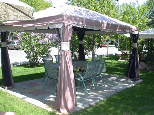 a gazebo with chairs and a table in the grass at Motel Derfal in Repentigny