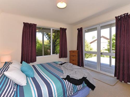 a bedroom with a bed and a large window at Tuis on Tata - Golden Bay Home Tata Beach in Tarakohe