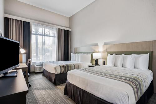 a hotel room with two beds and a flat screen tv at Country Inn & Suites by Radisson, Port Canaveral, FL in Cape Canaveral