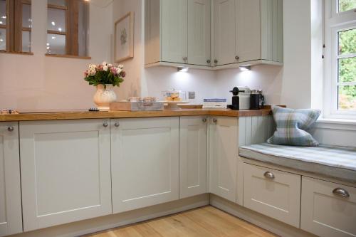 a kitchen with white cabinets and a vase of flowers at The Gardener's Cottage in Dunblane
