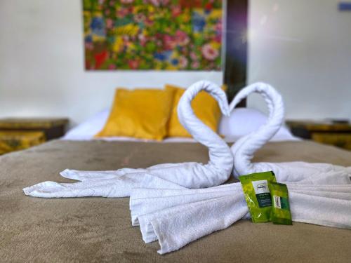a pair of towels and a towel swan on a bed at Vila Pequeá Ilhabela in Ilhabela