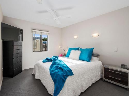 a bedroom with a bed with blue pillows and a tv at Roberts Retreat - Taupo Holiday Home in Taupo