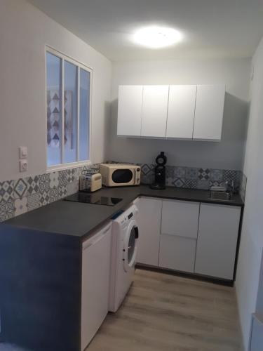 a kitchen with white cabinets and a washer and dryer at Le Chabin in Metz
