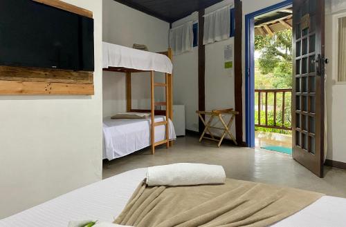 a bedroom with a bed and a bunk bed with a tv at Vila Pequeá Ilhabela in Ilhabela