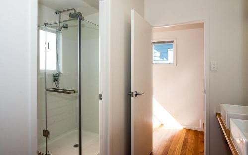 a glass shower door in a bathroom with a sink at Shoreside - Tutukaka Holiday Home in Tutukaka