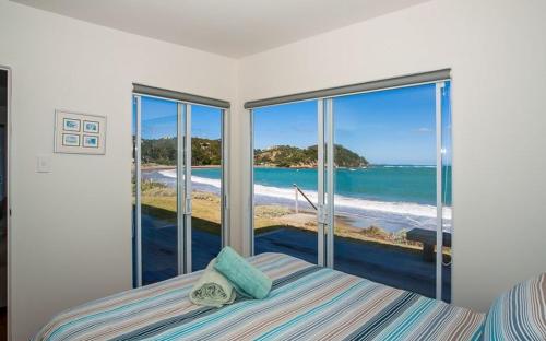 a bedroom with a bed with a view of the ocean at Shoreside - Tutukaka Holiday Home in Tutukaka