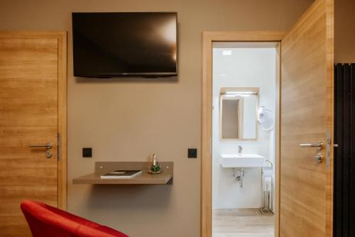 a room with a bathroom with a sink and a red chair at Rooms VERDE in Petrovče
