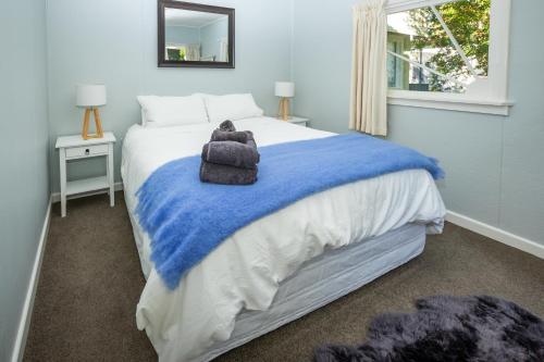 a bedroom with a bed with a teddy bear on a blue blanket at Hop, Skip and Jump to the Lake - Te Anau House in Te Anau
