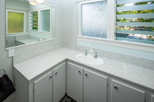 un bagno bianco con lavandino e specchio di Hop, Skip and Jump to the Lake - Te Anau House a Te Anau