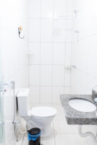 a white bathroom with a toilet and a sink at Pousada DDB in Resende Costa