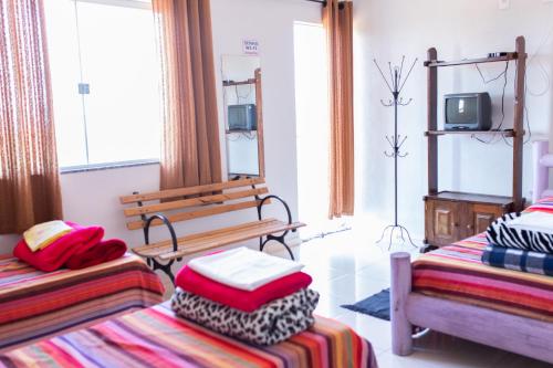 a room with two beds and a bench and a tv at Pousada DDB in Resende Costa