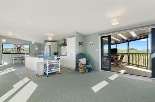 a kitchen and living room with a view of the ocean at The Blue Cottage with WiFi- Waipu Holiday Home in Waipu