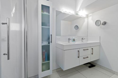 a white bathroom with a sink and a shower at Sea Shells By The Shaw - Waihi Beach Holiday Home in Waihi Beach
