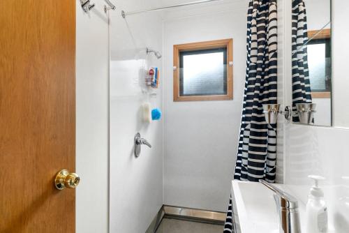 a bathroom with a shower with a black and white shower curtain at Heperi Haven - Waikanae Beach Holiday Home in Waikanae