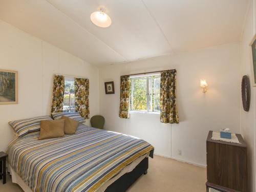 a bedroom with a bed and two windows at Southern Lakes Sweetie - Albert Town Bach in Wanaka