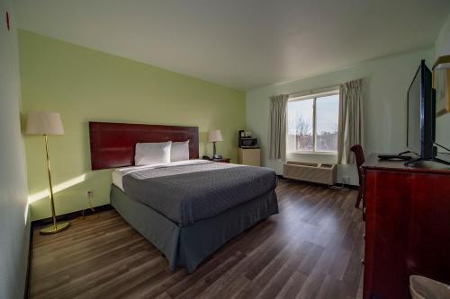Rodeway Inn Central Colorado Springs في كولورادو سبرينغز: غرفة نوم بسرير ونافذة كبيرة