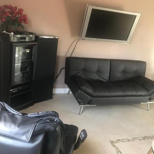 a living room with a leather couch and a flat screen tv at paradise luxury experience in Woodland Hills